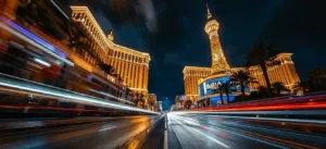 Night view of Las Vegas Strip with glowing neon lights reflecting on wet pavement, luxury casinos towering under a dark sky